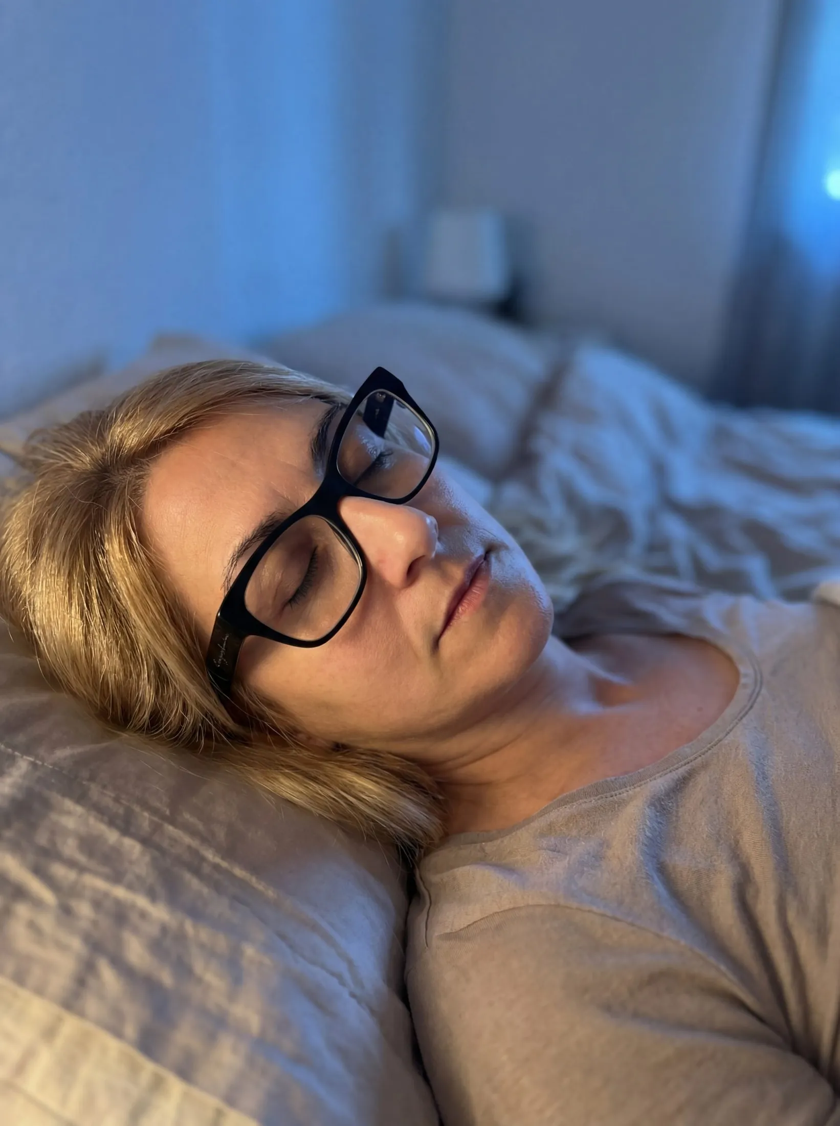 Melania Romanelli lying in bed with her eyes closed during a gentle bedtime yoga practice